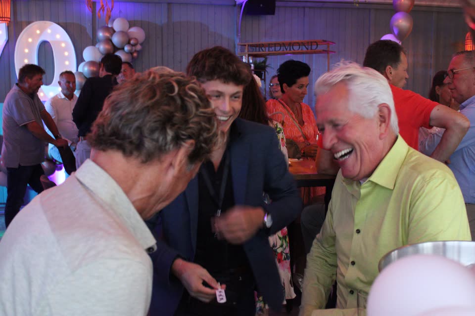 Sven Manders laat tijdens een feest van dichtbij een truc zien aan twee hartelijk lachende gasten